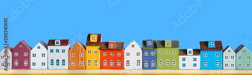 Row of wooden miniature colorful retro houses on blue solid background photo