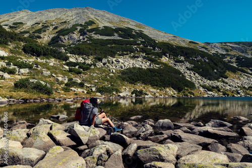 Woman sitting on the stones and resting at The Frog lake in Pirin mountain Selective focus photo