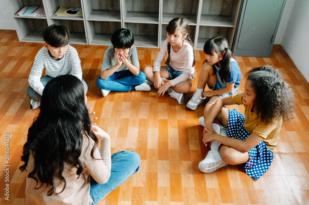 Elementary international students group sit cross legged in circle