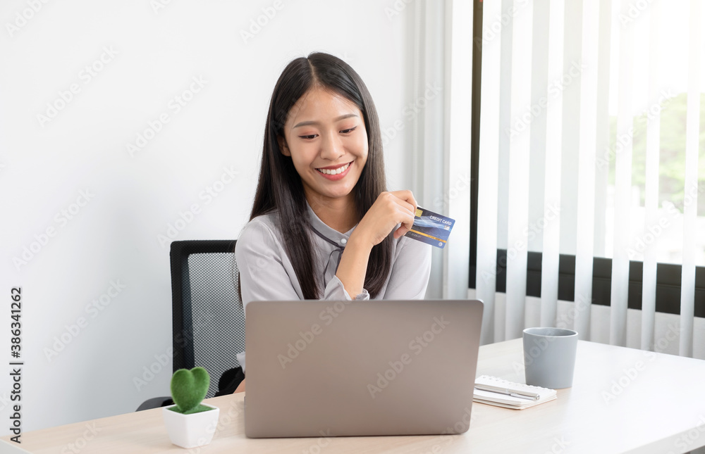 The Asian businesswoman's hand is holding a credit card and using a laptop for online shopping and internet payment in the office The Asian businesswoman's hand is holding a credit card and using a laptop for online shopping and internet payment in the office