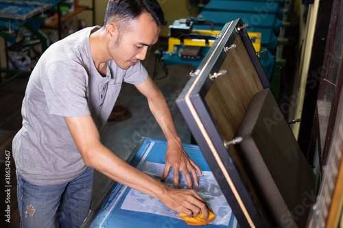 man worker preparing manual screen printing shirt