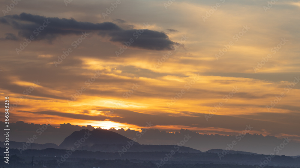 Silhouette of a hill against beautiful golden hour light and beautiful clouds formation in the horizon
