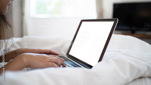 Women using laptop on bed after wake up in the morning.