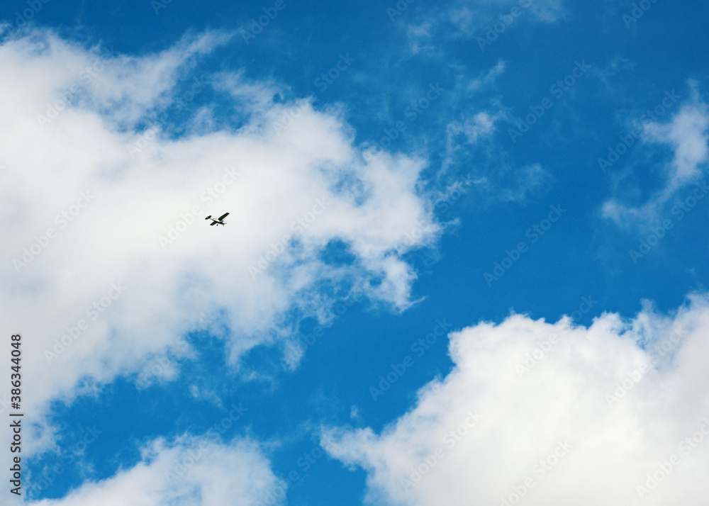 Airplane flies against a blue sky with clouds