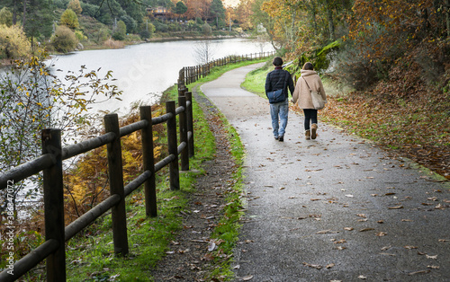 Scene of a couple walking backwards along a path in the countryside in autumn and near a lake. © csbphoto