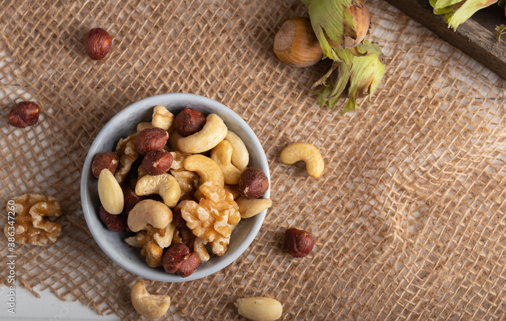 Fototapeta premium Variation of dried nuts on a autumn theme background with leafs and candle light.