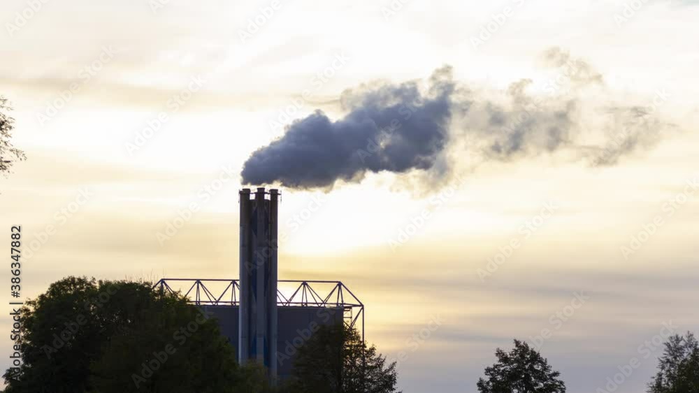Time lapse of smoking factory chimney against the background of a setting sun - slow zoom in Time lapse of smoking factory chimney against the background of a setting sun - slow zoom in