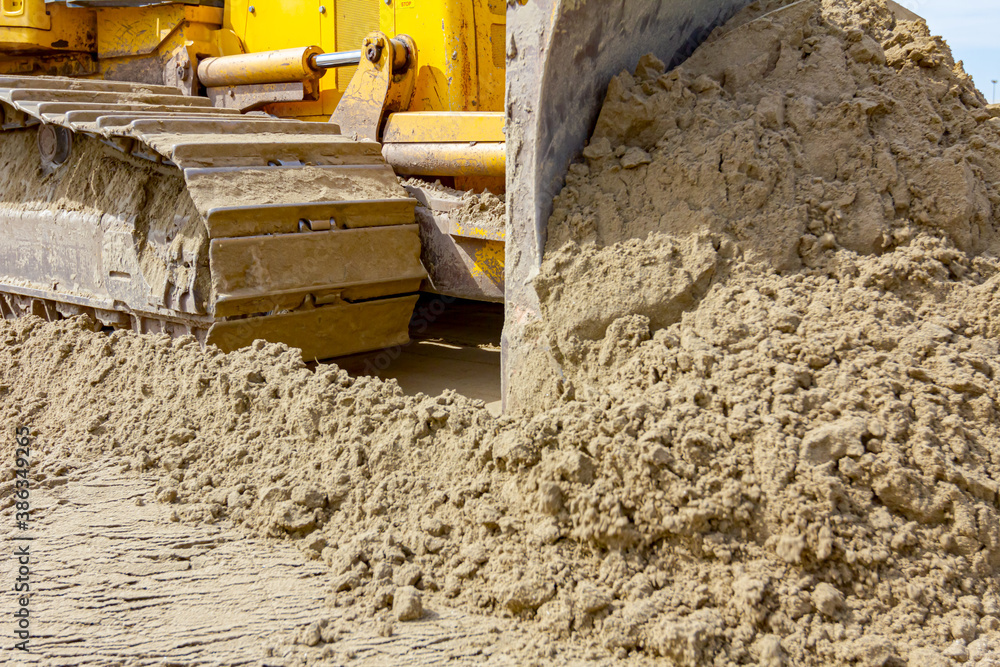 Fototapeta premium Crawler's tracks, bulldozer machine is leveling construction site