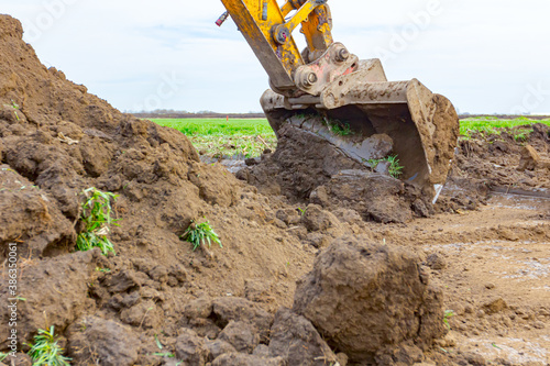 Excavator's front tool, bucket, blade, is excavating soil at building site