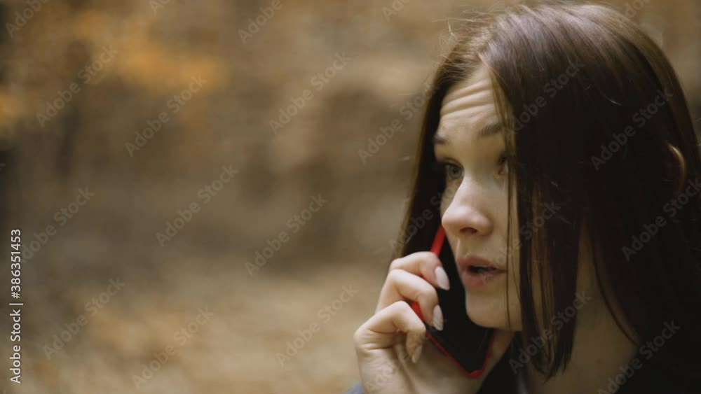 Black jacket white T-shirt she stands alone middle forest late yellow autumn. Serious, gloomy, talking red phone calling the police, rescue service, employer. Intense atmosphere, camera around woman Black jacket white T-shirt she stands alone middle forest late yellow autumn. Serious, gloomy, talking red phone calling the police, rescue service, employer. Intense atmosphere, camera around woman