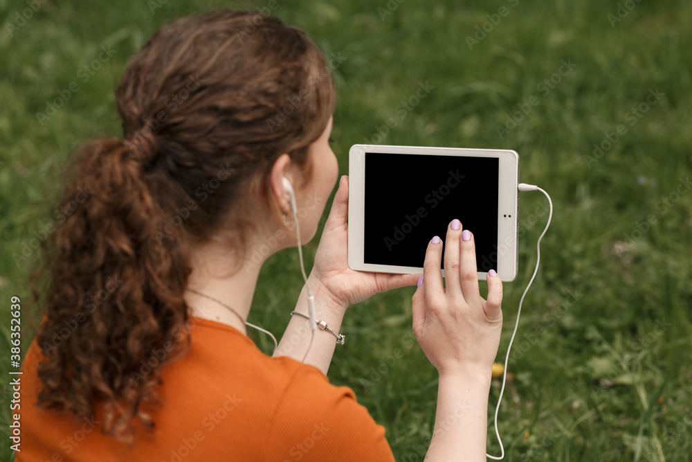 Mock up image of digital tablet pc with black screen and copy space. Young curly pretty girl using modern technologies for searching information on website in the internet.