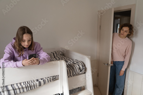 Fotografija Worried Caucasian mom control 12s teenage daughter using smartphone gadget