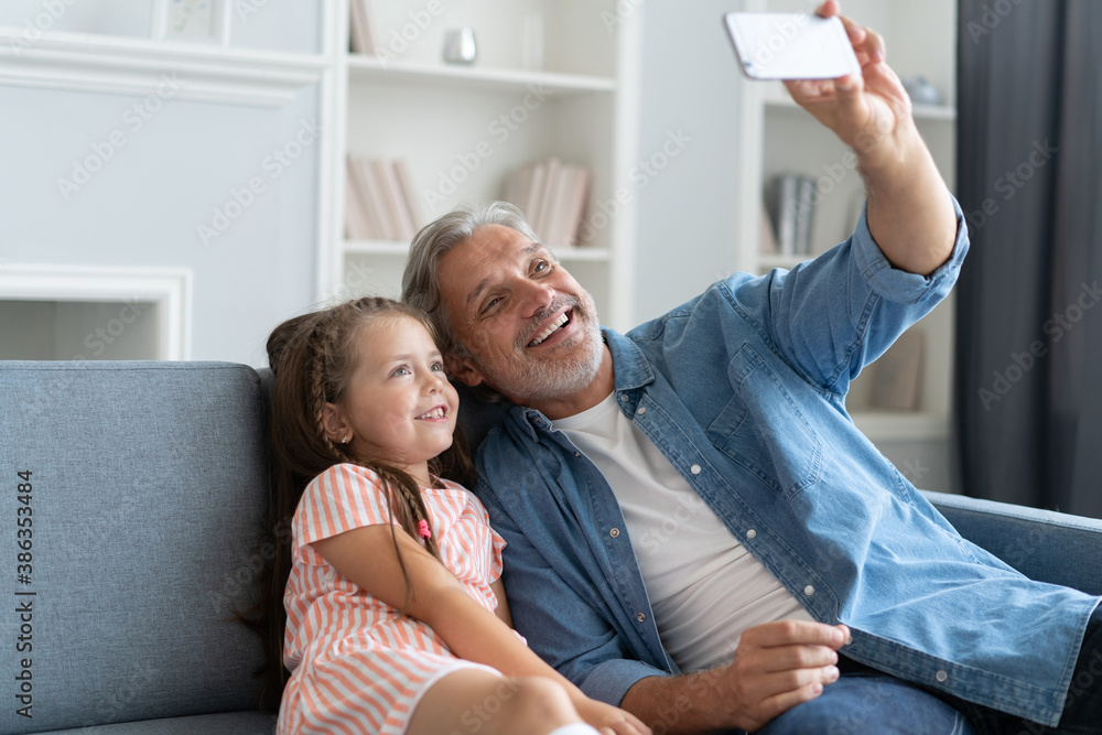 Funny selfie with dad. Self portrait of father and his little daughter taking selfie while sitting on the sofa Funny selfie with dad. Self portrait of father and his little daughter taking selfie while sitting on the sofa