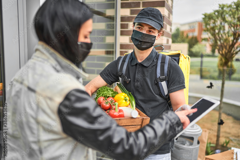 .The food delivery man delivered the online order from the store for the woman, they wearing protective masks .The food delivery man delivered the online order from the store for the woman, they wearing protective masks