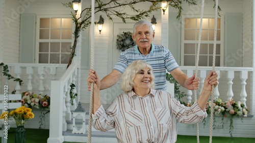 Senior couple together in front yard at home. Man swinging and hugging woman. Happy mature family © Andrii Iemelianenko