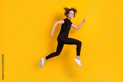 Full length body size profile side view of lovely cheerful slender girl jumping running fast isolated bright yellow color background