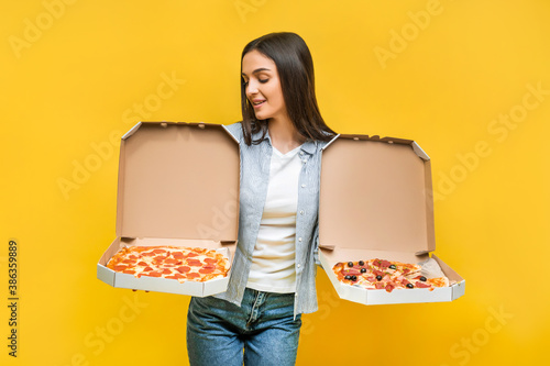 Girl on a yellow background holds two pizzas. Copy space