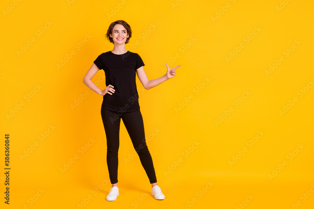 Full length body size view of nice attractive cheerful girl pointing aside copy empty space isolated bright yellow color background Full length body size view of nice attractive cheerful girl pointing aside copy empty space isolated bright yellow color background