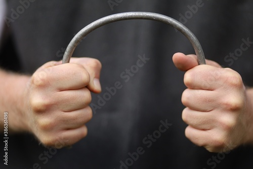 Strong hands bend a metal rod