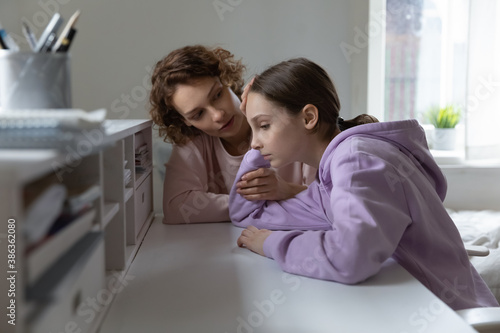 Loving Caucasian mom comfort support unhappy teenage 13s daughter feeling lonely at home. Caring mother cheer sad teen girl child suffering from school discrimination bullying. Loner concept. photo