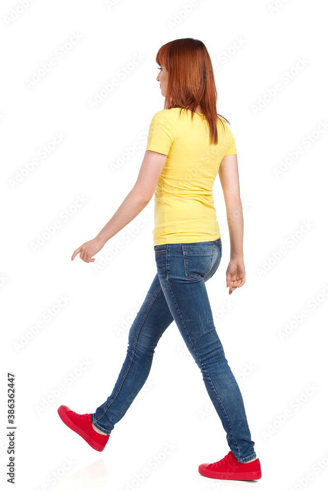 Waking Young Woman In Yellow Shirt, Jeans And Red Sneakers. Side View.