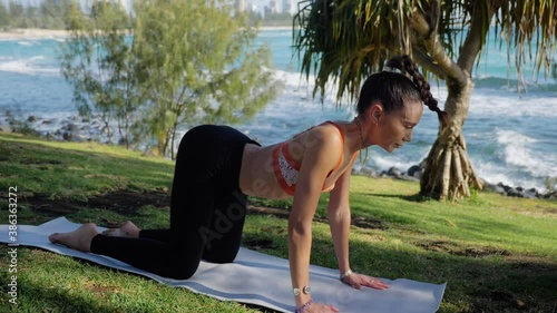 Yogi Doing Cat To Cow Pose At Burleigh Hill - Ocean Waves At Burleigh Heads Beach - Gold Coast, QLD, Australia. - medium shot photo