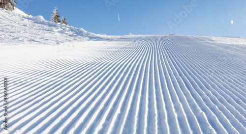 Close-up straight line rows of freshly prepared groomed ski slope piste.