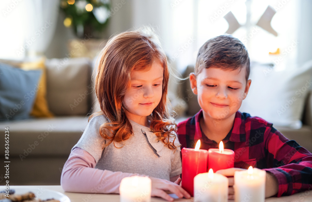 Small girl and boy indoors at home at Christmas, holding candles. Small girl and boy indoors at home at Christmas, holding candles.