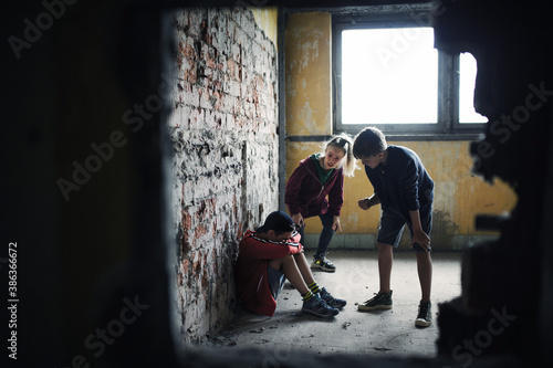 Teenage boy attacked by thugs in abandoned building, gang violence and bullying concept. photo