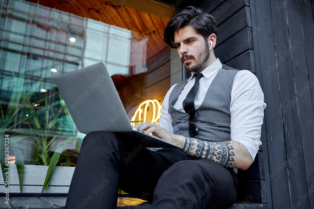 Businessman using a laptop outside on the city street Businessman using a laptop outside on the city street