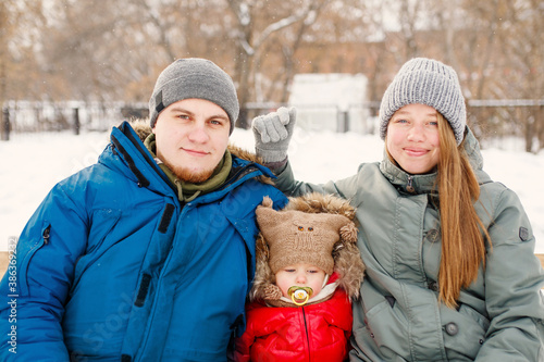 Close-up of young happy family with one toddler in winter casual oufit posing outdoors photo