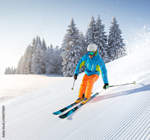 Skier skiing downhill during sunny day in high mountains