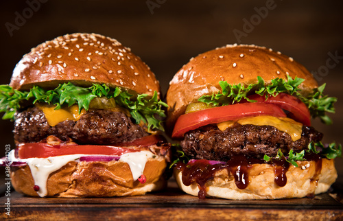 Close-up of home made tasty burgers on wooden table.