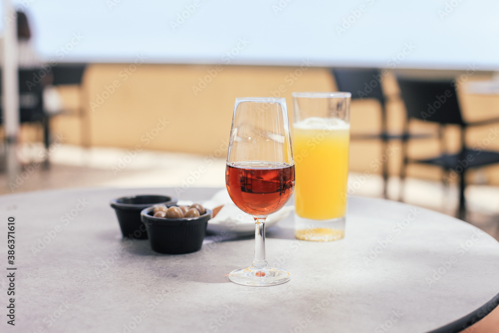 A glass of Madeira wine and orange juice on an outdoor table with traditional snacks