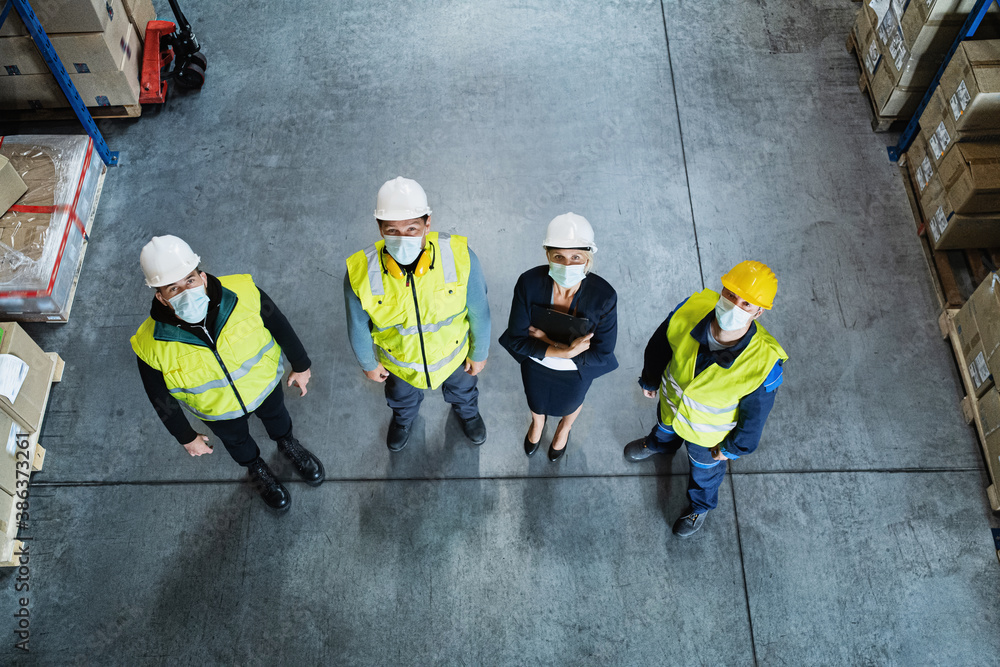 Fototapeta premium Top view of group of workers with manager indoors in warehouse, coronavirus concept.