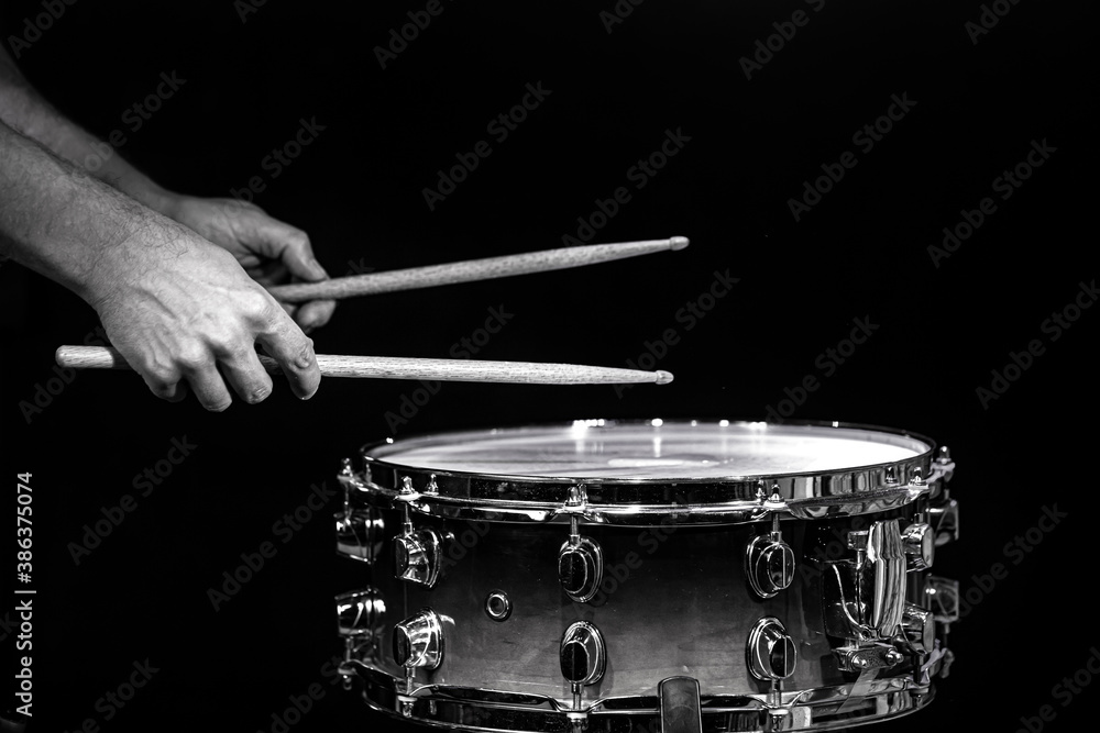Obraz premium Drum sticks hitting snare drum with splashing water on black background under studio lighting. Black and white. Close up.