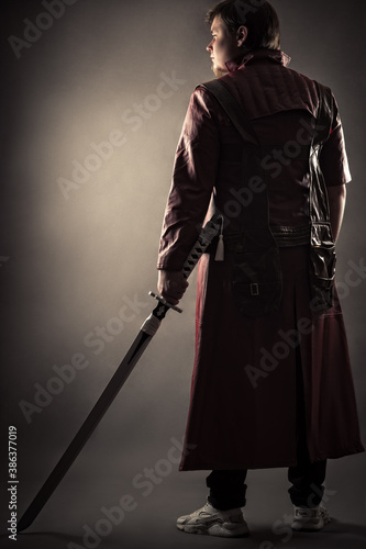 person in jacket with sword standing back