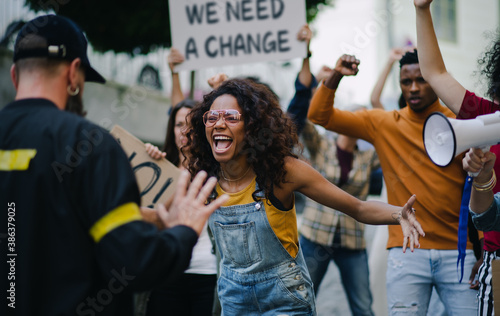 Police stopping group of people activists with raised fists protesting on streets, BLM demonstration concept.