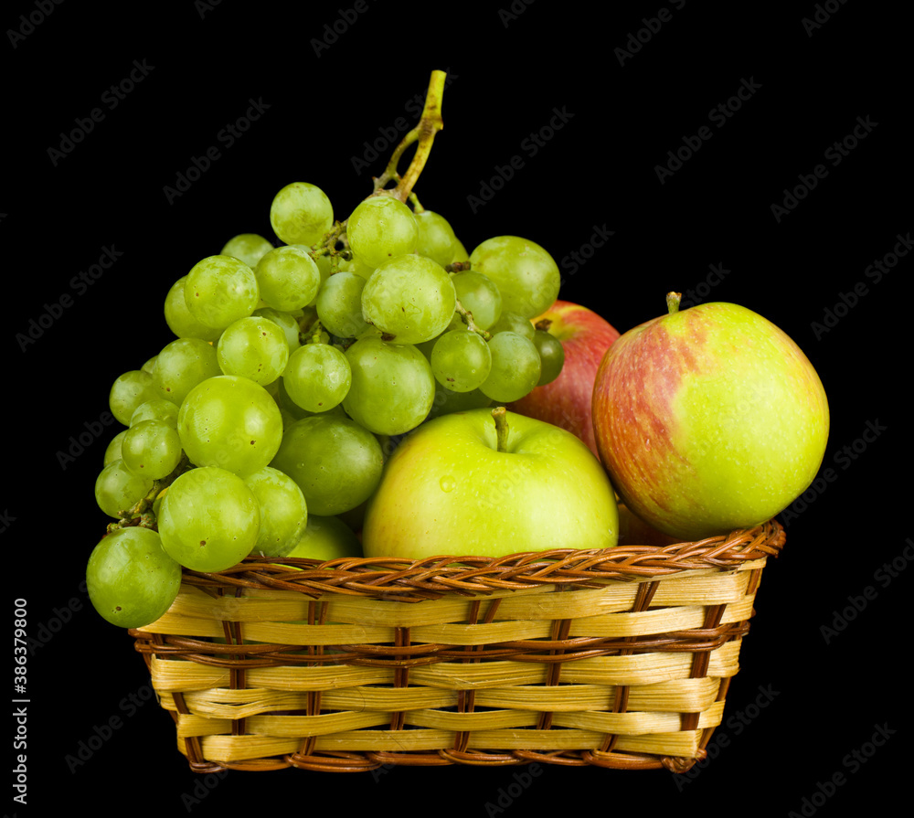 Grapes and apples in a basket isolated on a black background close-up. Grapes and apples in a basket isolated on a black background close-up.