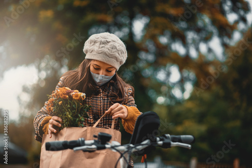 Teenage girl in protective face mask riding bicycle. Teenage girl, volunteer, delivering groceries. 