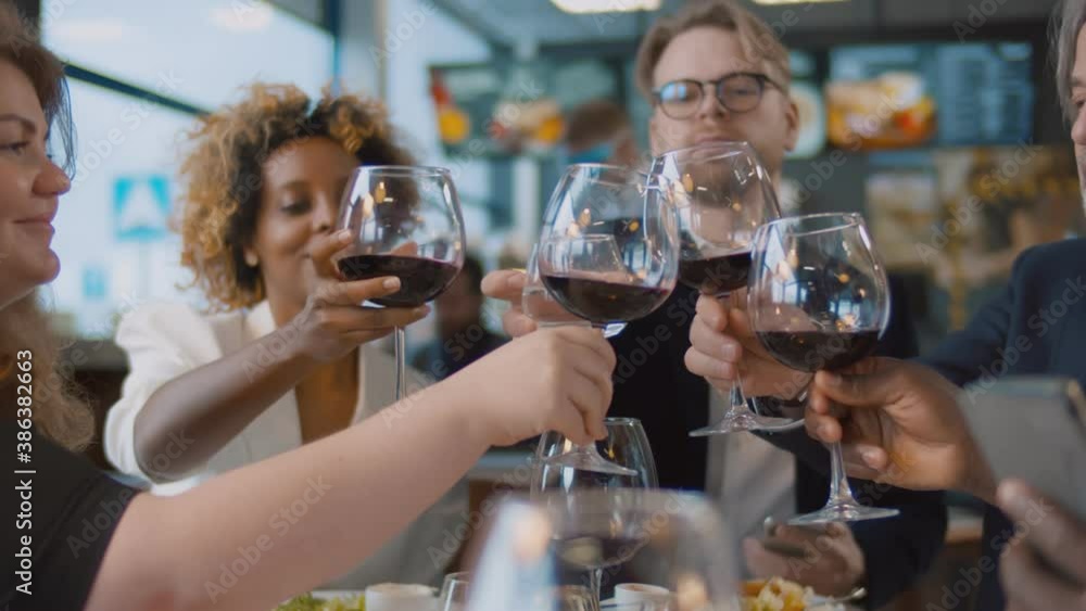 Man with glass of water cheers with diverse friends drinking red wine at bar restaurant Man with glass of water cheers with diverse friends drinking red wine at bar restaurant