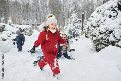 A cute children playing in snow outdoor near the christmas trees