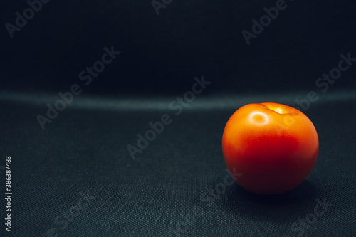 Single tomato on black background. Vegetable, shiny, studio, shallow focus, blur, one, 1, individual, dark, lighting, contrast.