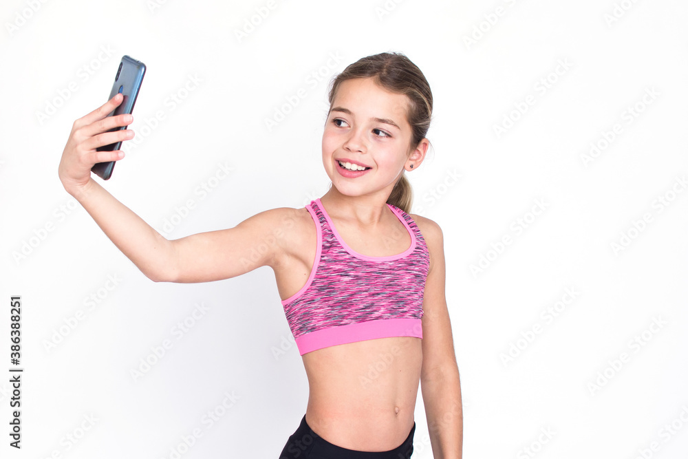 Beautiful slim young sport and healthy girl in sportswear makes selfie with cellphone. Isolated photo on white background with copy space. Beautiful slim young sport and healthy girl in sportswear makes selfie with cellphone. Isolated photo on white background with copy space.