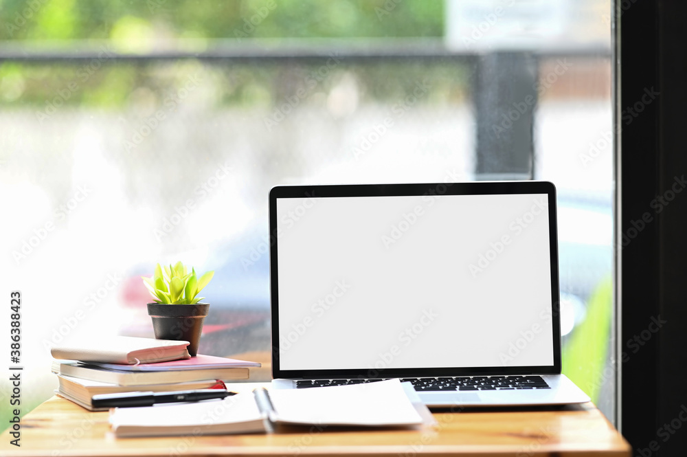Workspace with blank screen desktop laptop, plant and notebooks on wooden desk. Workspace with blank screen desktop laptop, plant and notebooks on wooden desk.