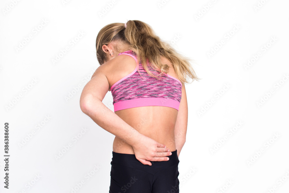 Young spotr girl suffering from backache isolated on white background. Female person in sportswear with back pain. Copy space. Young spotr girl suffering from backache isolated on white background. Female person in sportswear with back pain. Copy space.