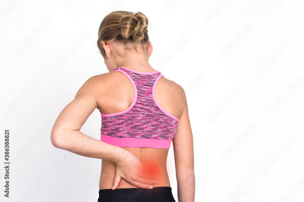 Young spotr girl suffering from backache isolated on white background. Female person in sportswear with back pain. Medical advertising concept with copy space. Young spotr girl suffering from backache isolated on white background. Female person in sportswear with back pain. Medical advertising concept with copy space.