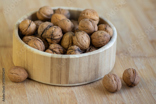 Walnuts on table in hard nutshells, group of dry ripened fruits in bowl, crop food ingredients ready for cooking