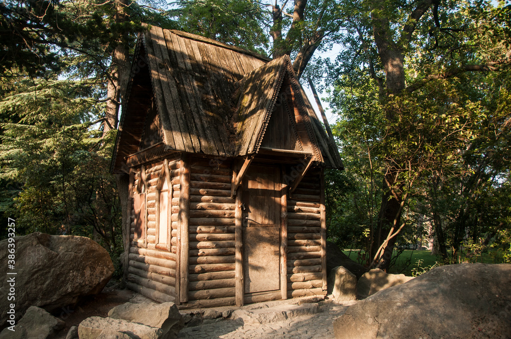 A small wooden hut with carved frames among the rocks in the forest. Fairytale house. A small wooden hut with carved frames among the rocks in the forest. Fairytale house.