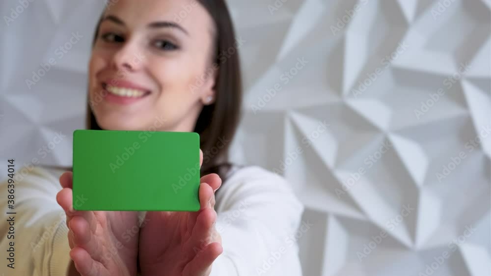 Beautiful brunette girl smiles and shows an element for advertising, with a green screen, on a white volumetric background Beautiful brunette girl smiles and shows an element for advertising, with a green screen, on a white volumetric background
